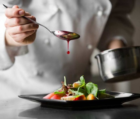 Chef serving food and drizzling with sauce